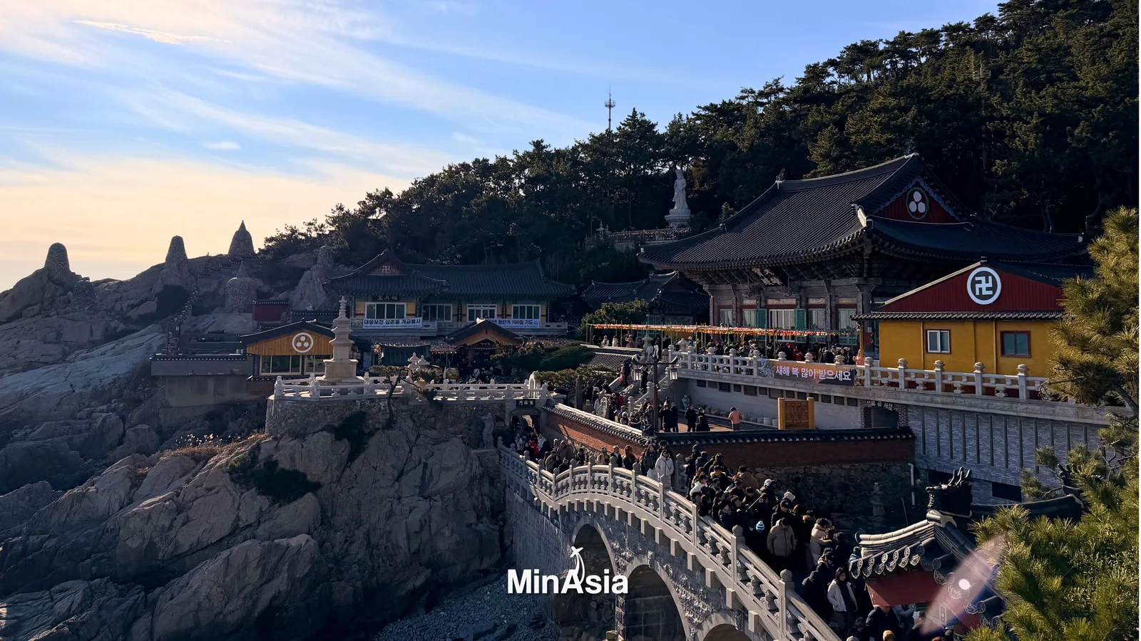 Praia de Haeundae em busan coreia do sul, durante o pôr do sol, com o horizonte da cidade ao fundo e turistas desfrutando da costa arenosa.