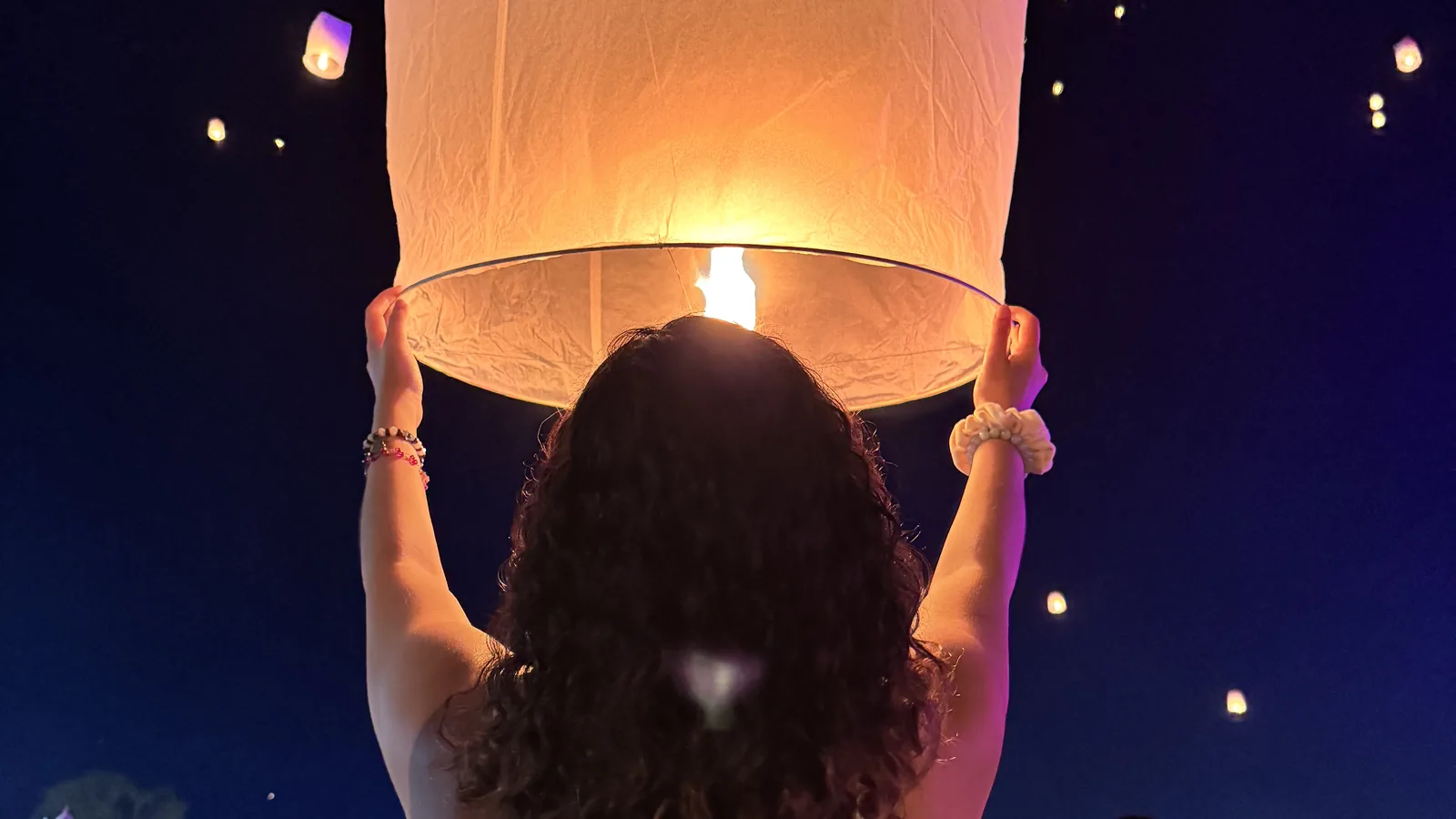 Uma família solta uma lanterna durante o festival das lanternas Tailândia, com krathongs flutuando no rio. Captura a alegria e a importância cultural do evento.