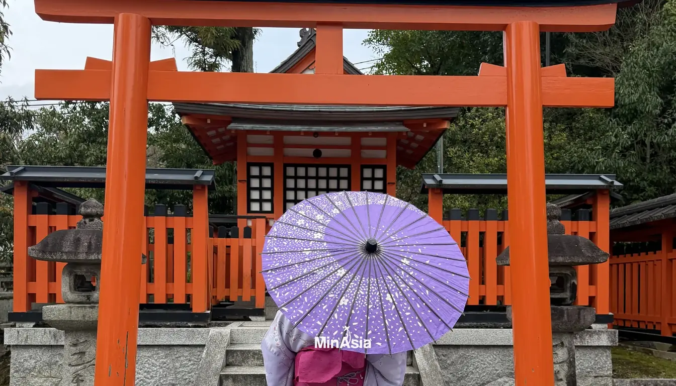 Entrada principal iluminada a noite do templo Fushimi Inari com lanternas acesas.